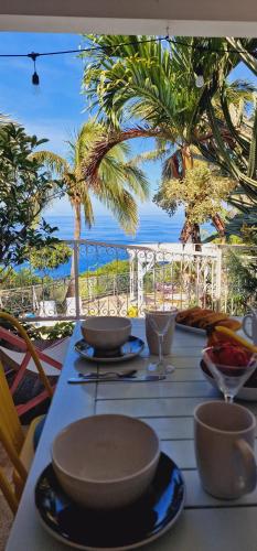 a table with plates and bowls on a table with the ocean at LA BOHEME, résidence de 5 appartements avec piscine, vue océan, Petite Ile in Petite Île