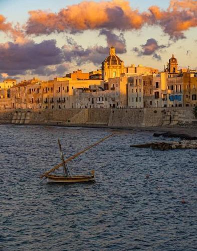 a small boat in the water in front of a city at Home Sisters in Trapani