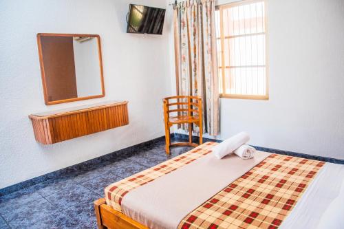 a bedroom with a bed and a mirror and a chair at Hotel Espor CA in Barinas
