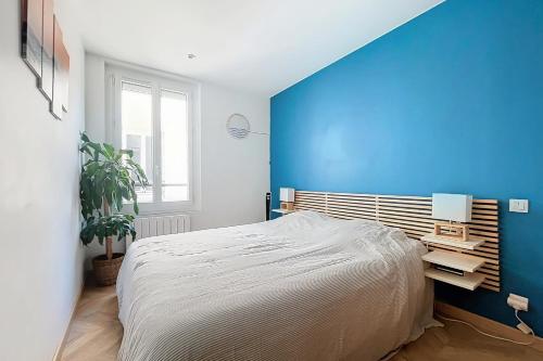une chambre avec un grand lit et un mur bleu dans l'établissement Charming 2-Room Paris Getaway Near Le Marais, à Paris