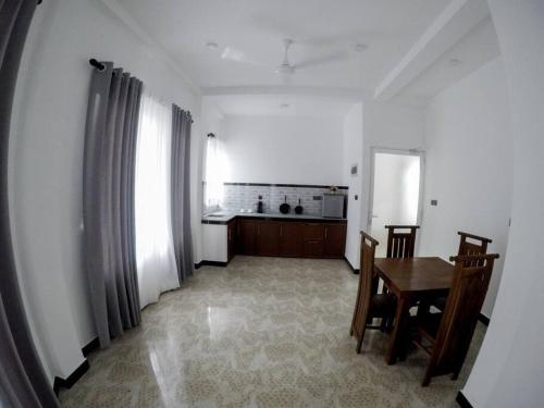 a living room with a table and a kitchen at Sambo White House Hikkaduwa - 5BD Entire Villa in Galle
