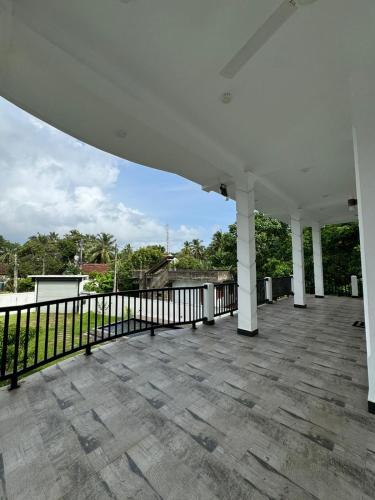 a large white porch with a black fence at Sambo White House Hikkaduwa - 5BD Entire Villa in Galle