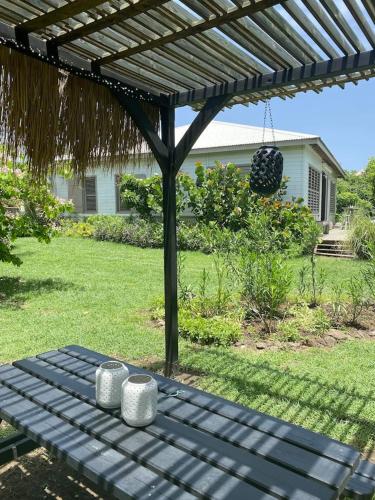a picnic table under a pergola in a yard at Villa moderne avec piscine à Le Vauclin in Le Vauclin