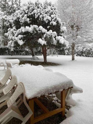 un banc recouvert de neige dans un parc dans l'établissement Maison Étoile - Explore Oisans, Fabulous house for 10 guests, Allemond, à Allemont
