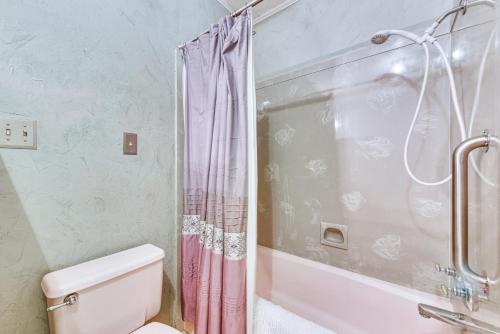 a bathroom with a pink shower curtain and a toilet at 8 Mi to Lafayette Dog-Friendly Home with Large Yard in Broussard