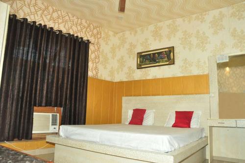a bedroom with a bed with white sheets and red pillows at Hotel Radhika Inn in Lucknow