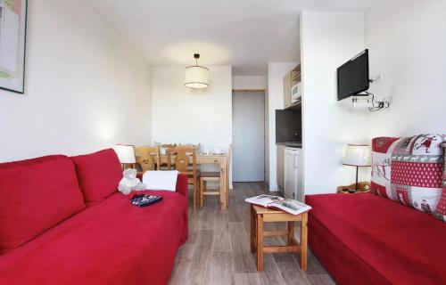 un salon avec un canapé rouge et une table dans l'établissement Résidence La Licorne - maeva Home - Studio 4 personnes - Confort MAE-8701, à La Plagne