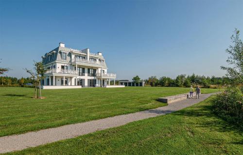 two people walking down a path in front of a large house at Cozy Apartment In Kamperland in Kamperland