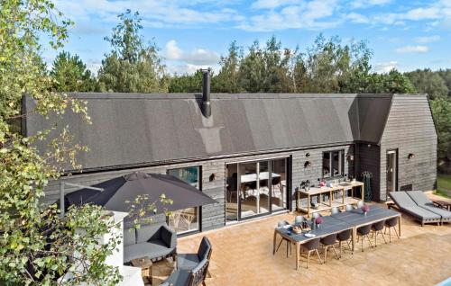 a house with a black roof with tables and chairs at Lovely Home In Væggerløse With Sauna in Marielyst
