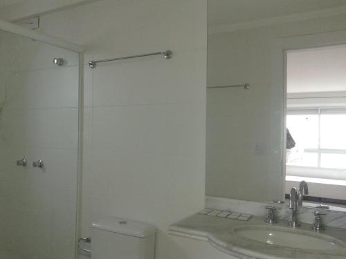 a bathroom with a toilet and a sink and a mirror at Apartamento no 20 piso com 90m2 e linda vista in Torres