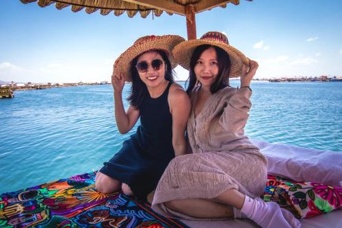 two women sitting next to the water on a boat at Uros mojsa lodge in Puno