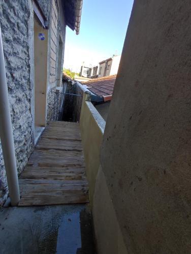 une passerelle en bois à côté d'un bâtiment avec un mur dans l'établissement Duplex quartier Saint Ruf proche remparts Avignon centre, à Avignon