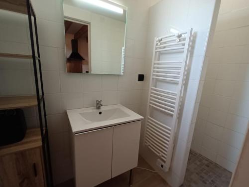 une salle de bain blanche avec un lavabo et un miroir dans l'établissement Duplex quartier Saint Ruf proche remparts Avignon centre, à Avignon
