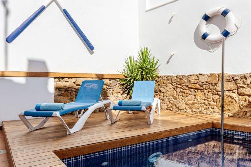 two chairs sitting on a deck next to a swimming pool at Casa Marinera en Palamós in Palamós