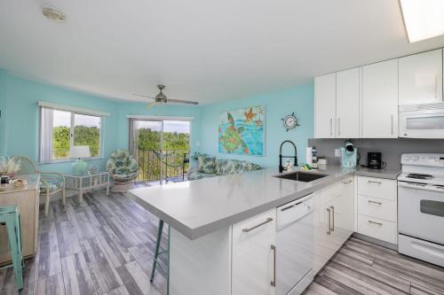 a kitchen with white cabinets and blue walls at Paradise Palms Ocean Pointe 1206 in Key Largo