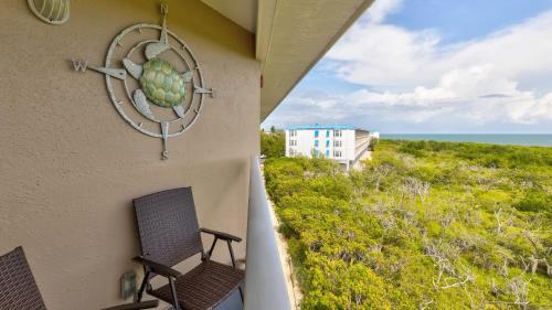 a balcony with two chairs and a view of the ocean at Sea View and Sunrise Top Floor Ocean Pointe 2412 in Key Largo