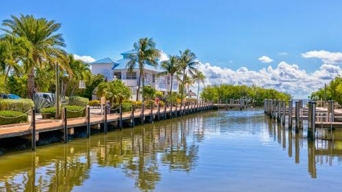 a bridge over a river with palm trees and a house at Sea View and Sunrise Top Floor Ocean Pointe 2412 in Key Largo