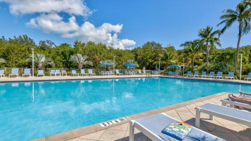 a large swimming pool with chairs and palm trees at Key Largo Sunrise Resort Style Ocean Pointe 5315 in Key Largo