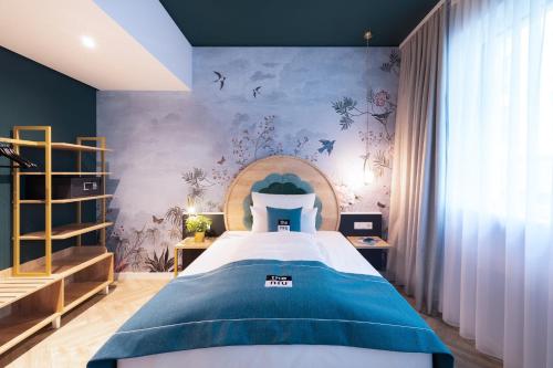 a bedroom with a bed and a wall with birds at Holiday Inn - the niu, Flower Konstanz by IHG in Konstanz