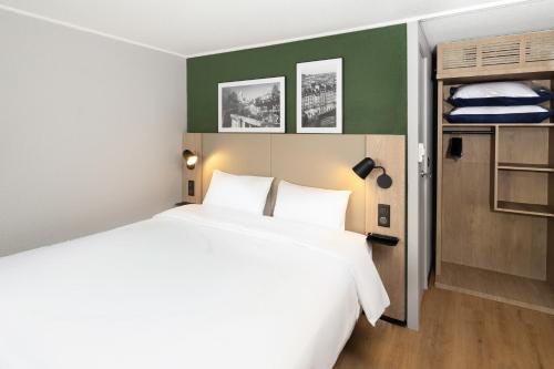 a bedroom with a white bed and a green wall at Campanile NATURE - Cergy Saint Christophe in Cergy