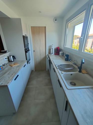 une cuisine blanche avec un évier et une fenêtre dans l'établissement T4 Familial dans résidence calme à proximité de la mer, à Cavalaire-sur-Mer
