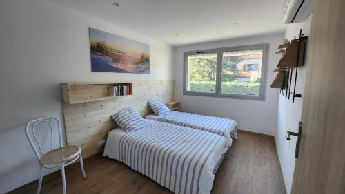 une chambre avec un lit, une chaise et une fenêtre dans l'établissement T4 Familial dans résidence calme à proximité de la mer, à Cavalaire-sur-Mer