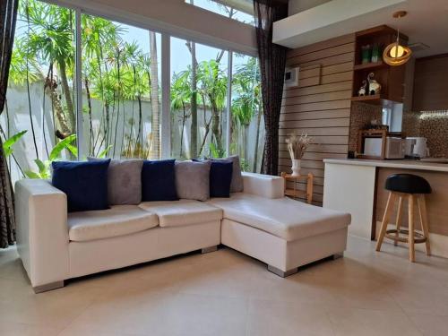 a living room with a white couch and large windows at ที รีสอร์ท ป่าหล่ายv1 in Ban Suan