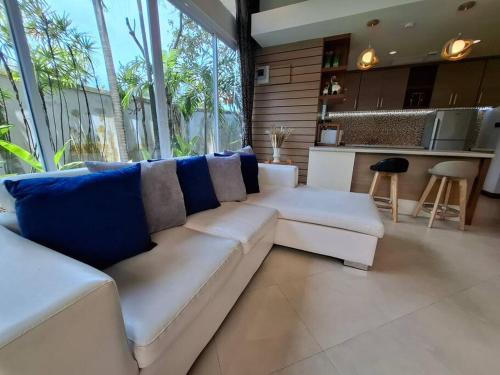 a living room with a white couch with blue pillows at ที รีสอร์ท ป่าหล่ายv1 in Ban Suan