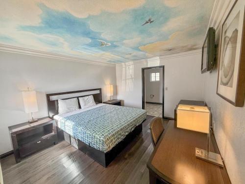 a bedroom with a bed and a painting on the ceiling at Super 7 Motel - Anaheim Packing District & Disneyland in Anaheim