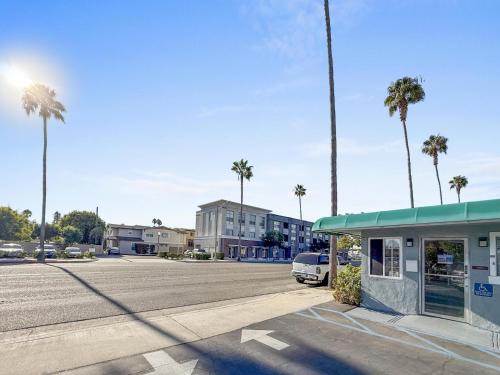 a parking lot with a building and palm trees at Super 7 Motel - Anaheim Packing District & Disneyland in Anaheim
