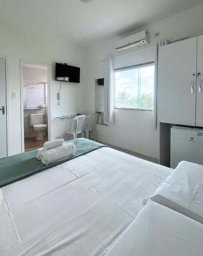 a white bedroom with a large bed and a window at Casamar Pousada in Paulista