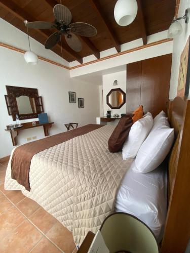 a bedroom with a large bed with a ceiling fan at La Buena Vibra Retreat and Spa Hotel in Tepoztlán