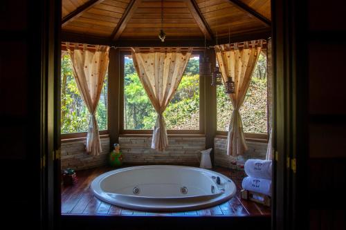 eine große Badewanne in einem Raum mit Fenstern in der Unterkunft Pousada Moriá in Visconde De Maua