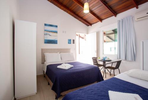 a hotel room with two beds and a table with a table at Pousada Doce Encanto in Florianópolis