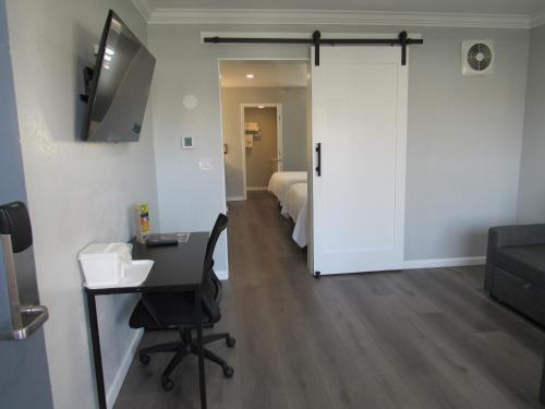a room with a desk and a room with a bed at Capri Suites Anaheim in Anaheim