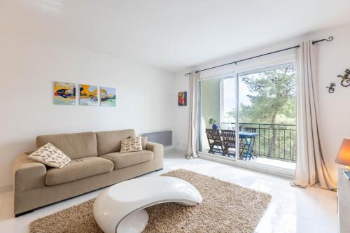 un salon avec un canapé et une grande fenêtre dans l'établissement LB Vacation Rentals I Spacious 2BR Apartment with Terrace, Balcony, à Mougins