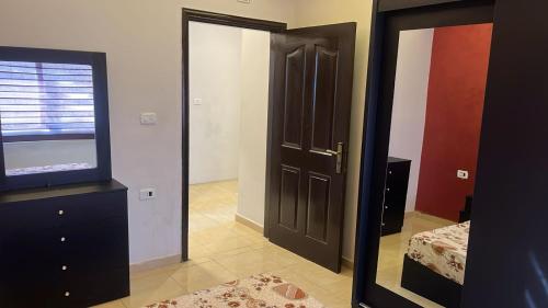 a bedroom with a mirror and a door and a television at Izz AlDin Tamimi St شقة مفروش سوبر ديلوكس الجبيهة in Ţāb Kirā‘