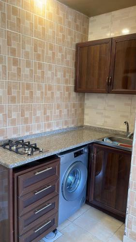 a kitchen with a washing machine and a sink at Izz AlDin Tamimi St شقة مفروش سوبر ديلوكس الجبيهة in Ţāb Kirā‘