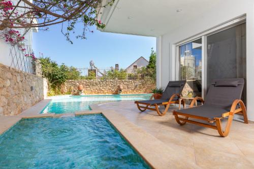 a swimming pool with two lounge chairs and a house at Helios Residence by A&D Properties in Porto Rafti