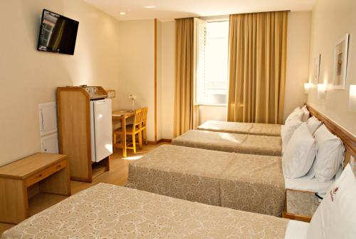 a hotel room with two beds and a table at Hotel Regina Rio de Janeiro in Rio de Janeiro