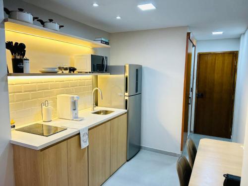 a small kitchen with a sink and a refrigerator at Studio Pé na areia - Icaraí in Niterói