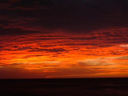 an orange sunset in the sky over the ocean at Posada la Arcadia in Pedro Gonzalez