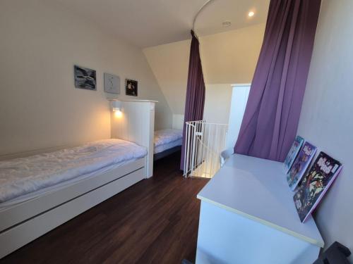 - une chambre avec 2 lits et des rideaux violets dans l'établissement Appartement Vue Mer, à Guidel