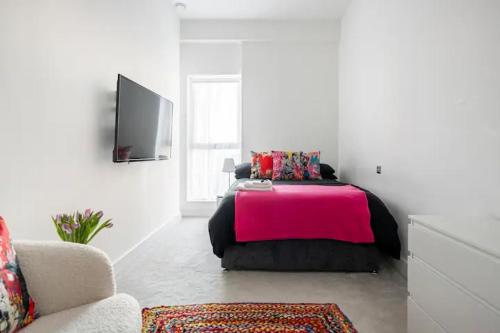a bedroom with a pink bed and a couch at Superb 1-Bed Apartment in Hertfordshire in Welwyn Garden City