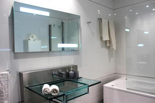 a bathroom with a glass sink and a tub at Madeira Home Spacious Accommodation in Funchal