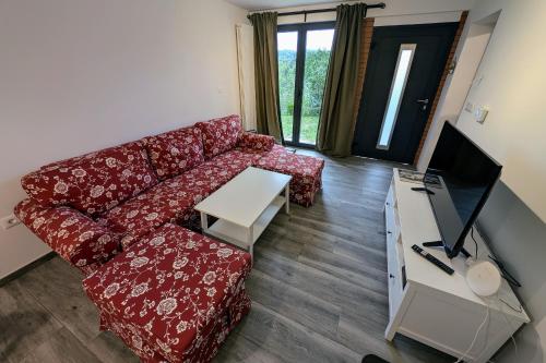 a living room with a red couch and a tv at Fuzine Lake Apartments in Fužine