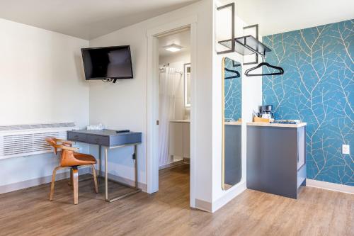 a room with a desk and a table and a tv at City Center Motel in Hamilton