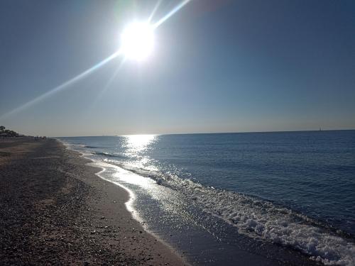 a beach with the sun shining on the water at Degli Angioini Holiday Home in Caulonia Marina