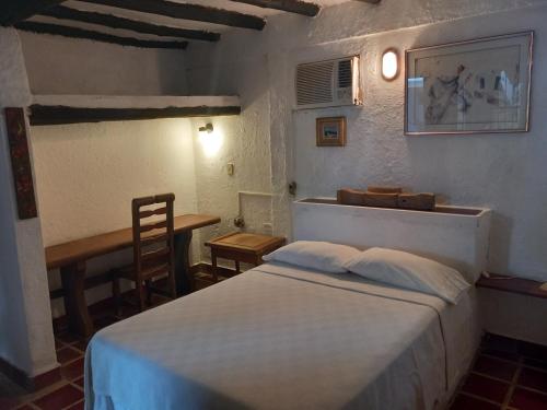 a bedroom with a bed and a table and a chair at Posada la Arcadia in Pedro Gonzalez