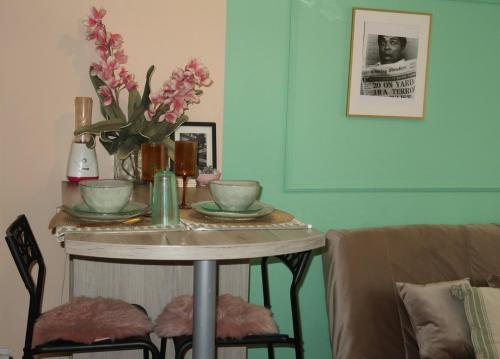 a table with two chairs and a table with flowers on it at M2 Suite by Central Park in Kragujevac